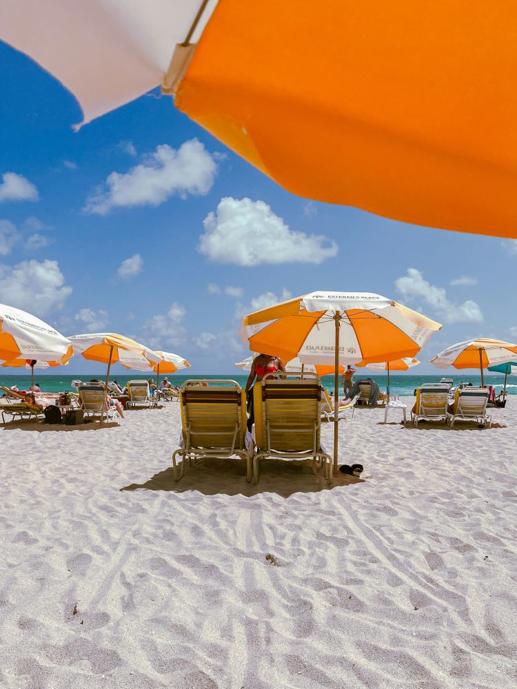 Beach chairs, colorful umbrellas, and white-sand Florida beach representing luxury seasonal living at a top Florida resort.